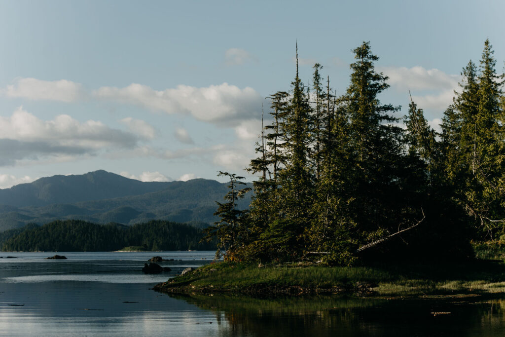An outcropping of land with pine trees sits in the coastal waters on Gitxaała territory with a ridge of mountains in the background. Photo by Paulina Otylia Niechel.